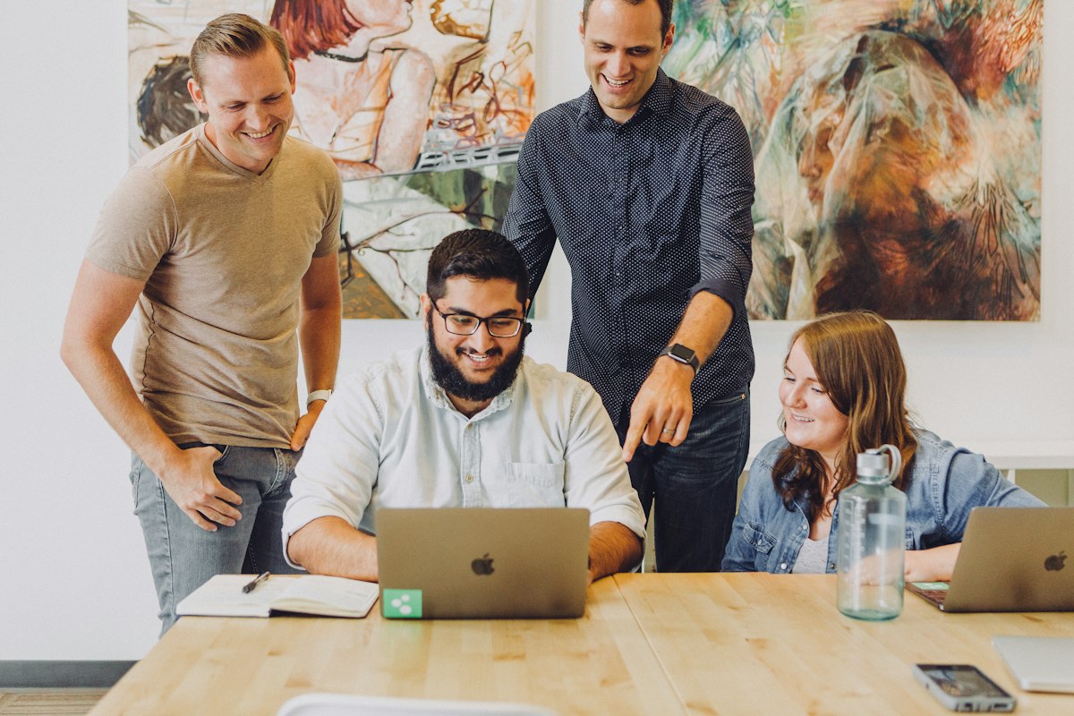 Team schaut gemeinsam lächelnd auf einen Laptop-Bildschirm